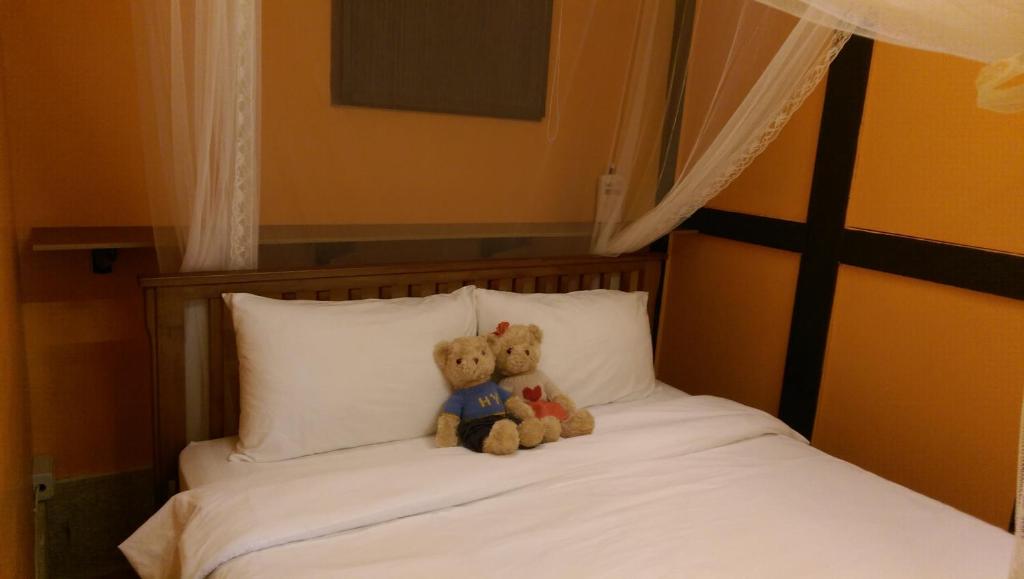 Dois ursos de peluche sentados em cima de uma cama em PianoPiano B&B em Jincheng