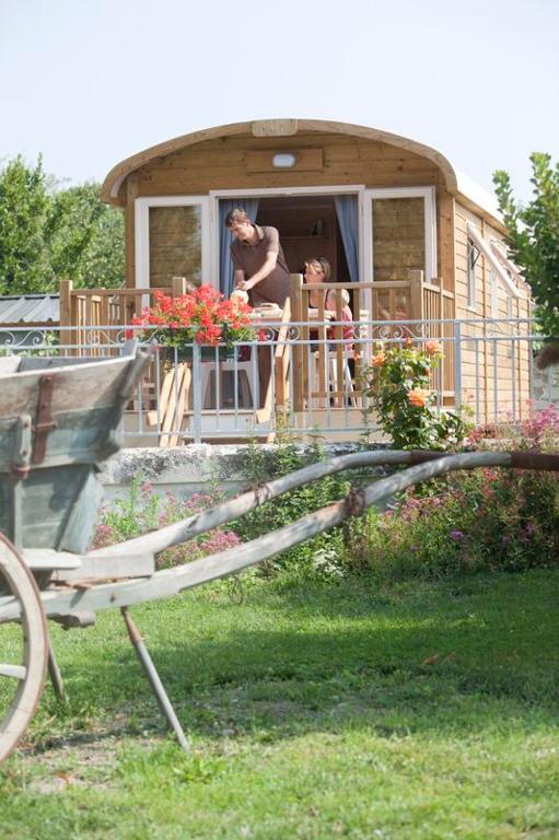 une femme debout sur la terrasse couverte d'une maison dans l'établissement Les Roulottes de Cuzay, à Roiffé