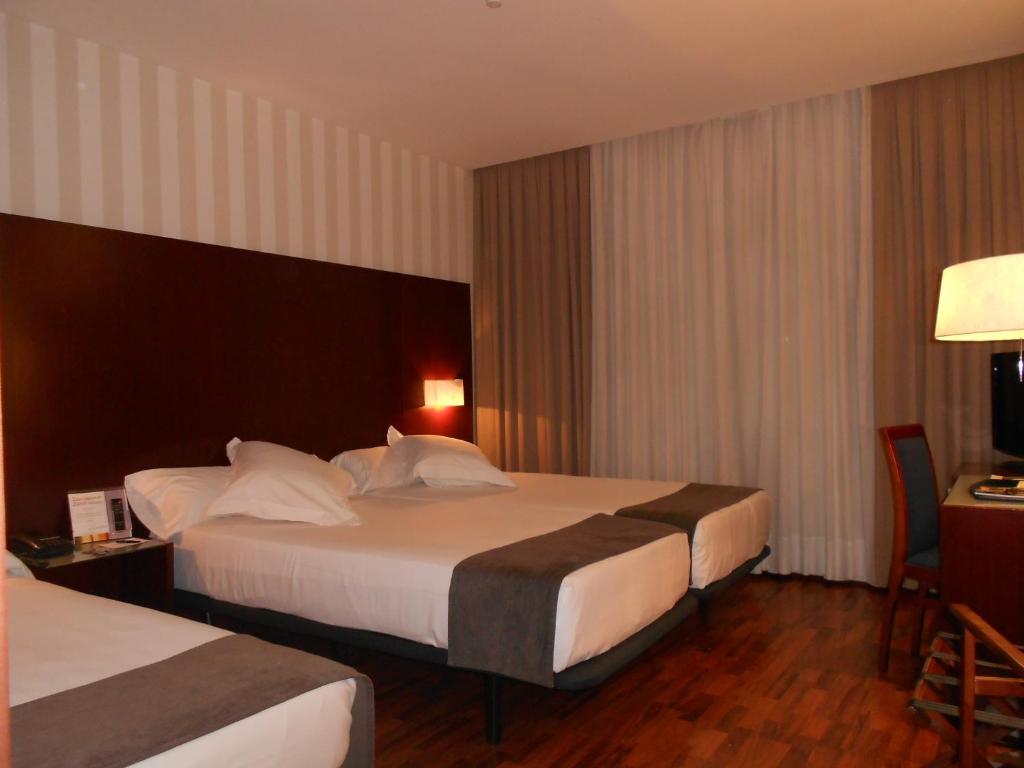 a hotel room with two beds and a desk at Zenit Málaga in Málaga