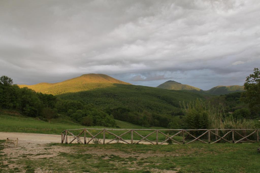 Ein Zaun auf einem Feld mit Bergen im Hintergrund in der Unterkunft Monolocale Borgo Antico in Castelnuovo di Val di Cecina