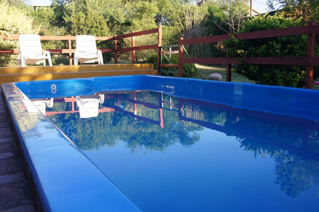 una piscina azul con sillas en un patio en La Herradura en Mina Clavero