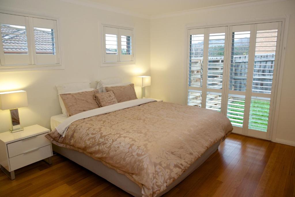 a white bedroom with a bed and two windows at Race Course Apartments in Yarra Glen