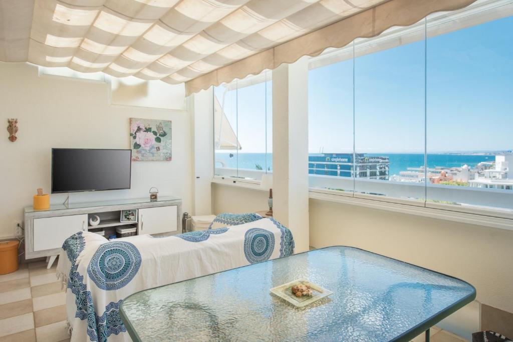 een kamer met een bed, een tafel en een televisie bij Ático La Marina in Marbella