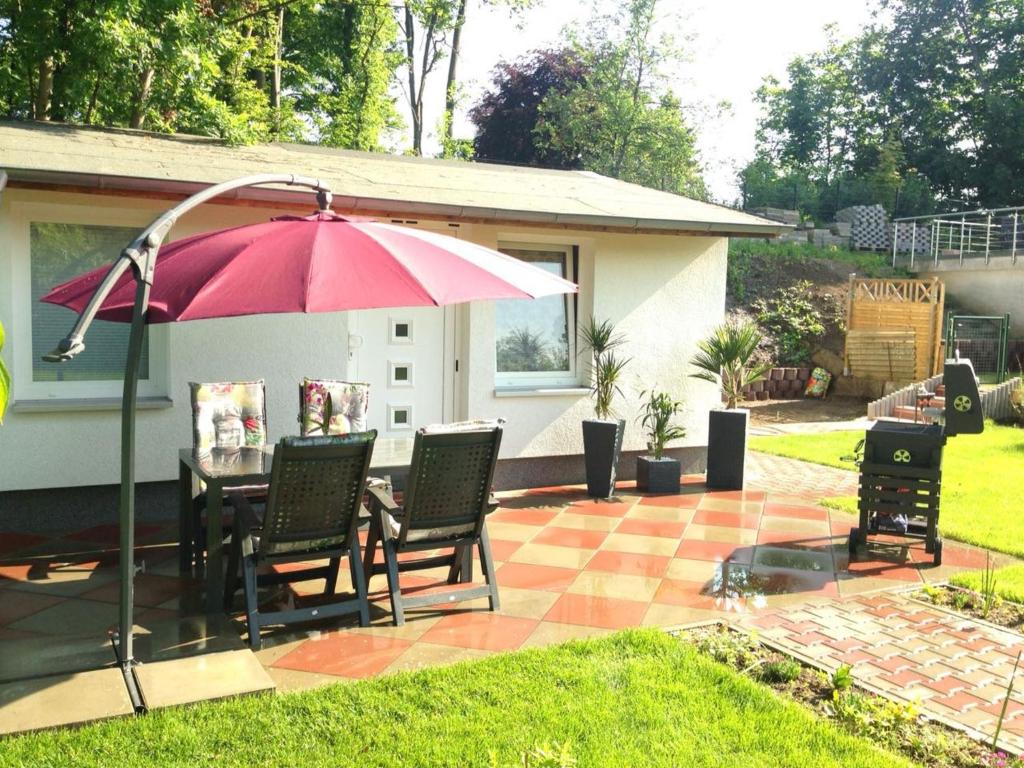 eine Terrasse mit einem Tisch, Stühlen und einem Sonnenschirm in der Unterkunft Ferienhaus Pankow klein in Berlin