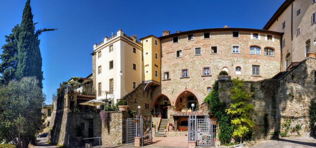 un grande edificio in pietra con una recinzione di fronte ad esso di Residence Le Santucce a Castiglion Fiorentino