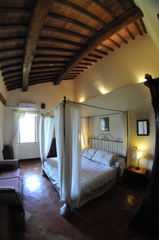 a bedroom with a bed with curtains in a room at Le Maribelle in Monticchiello