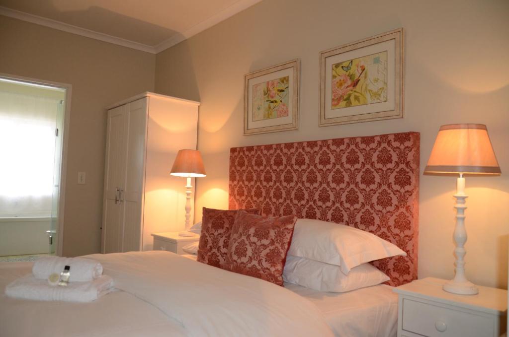een slaapkamer met een groot wit bed met 2 lampen bij The Winelands Guest House in Bellville