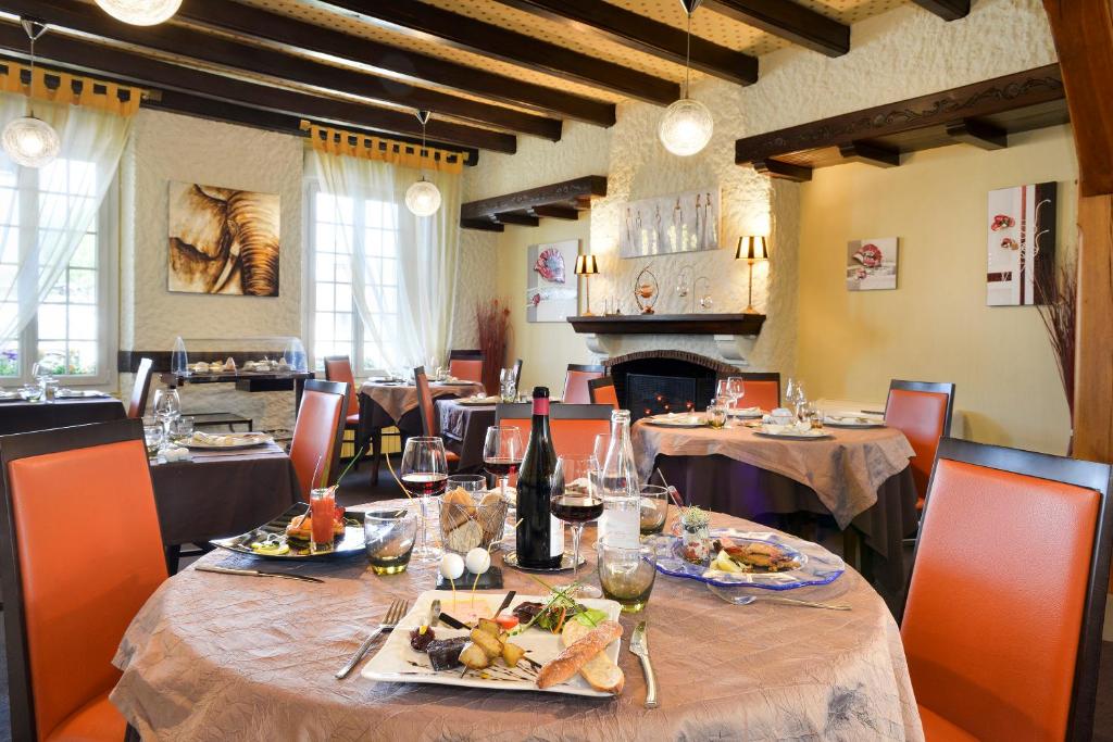 サルブリにあるLogis Hôtels Restaurant Le Dauphinのダイニングルーム(テーブル、食べ物、ワイン付)
