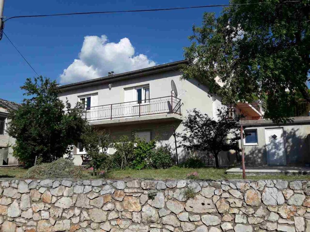 una gran casa blanca con un muro de piedra en Apartment Damir, en Senj