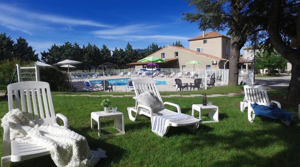 um grupo de cadeiras brancas sentadas na relva perto de uma piscina em VVF Haute Provence em Lagrand