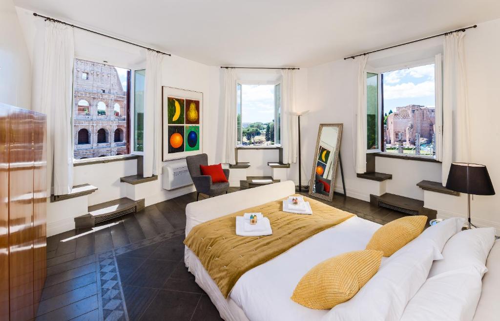 a bedroom with a large white bed and windows at Magia at Colosseum in Rome