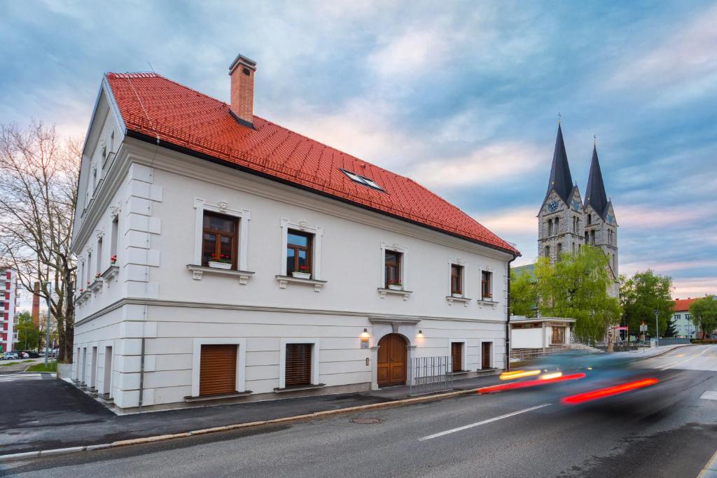 un edificio blanco con techo rojo y una iglesia en Hostel Bearlog Kočevje, en Kočevje