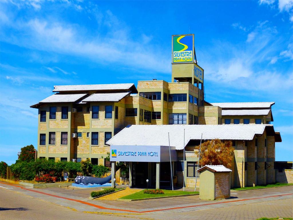 a large building with a sign on top of it at Silvestre Praia Hotel in Imbituba