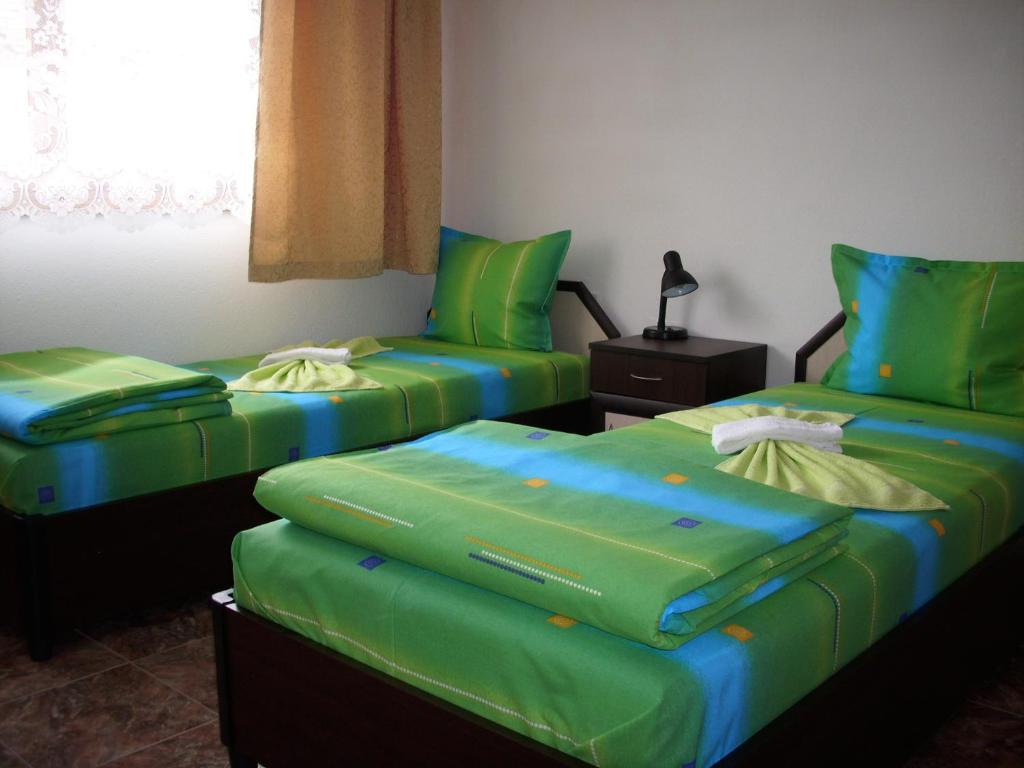 ポモリエにあるGeorgievi Guest Houseのベッド2台 緑のクッション付きの部屋