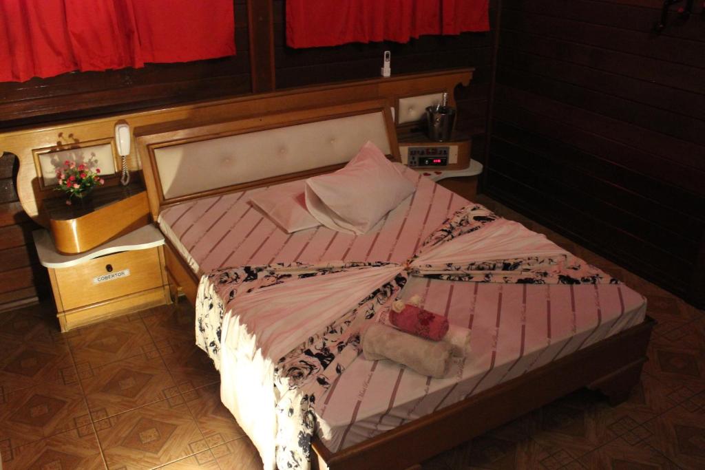 Motel Paradise (Adults only) في ساو جوزيه دوس كامبوس: غرفة نوم بسرير لحاف وردي وبيض