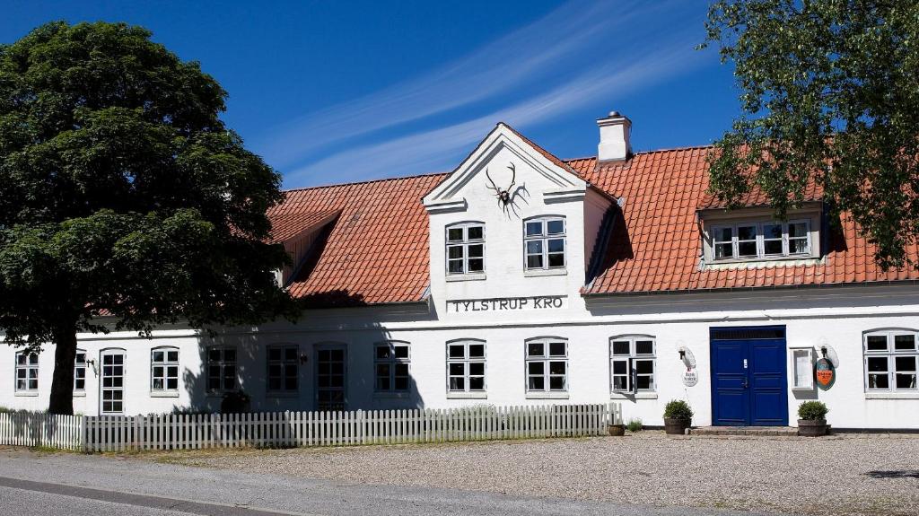un bâtiment blanc avec un toit rouge dans l'établissement Tylstrup Kro og Motel, à Tylstrup