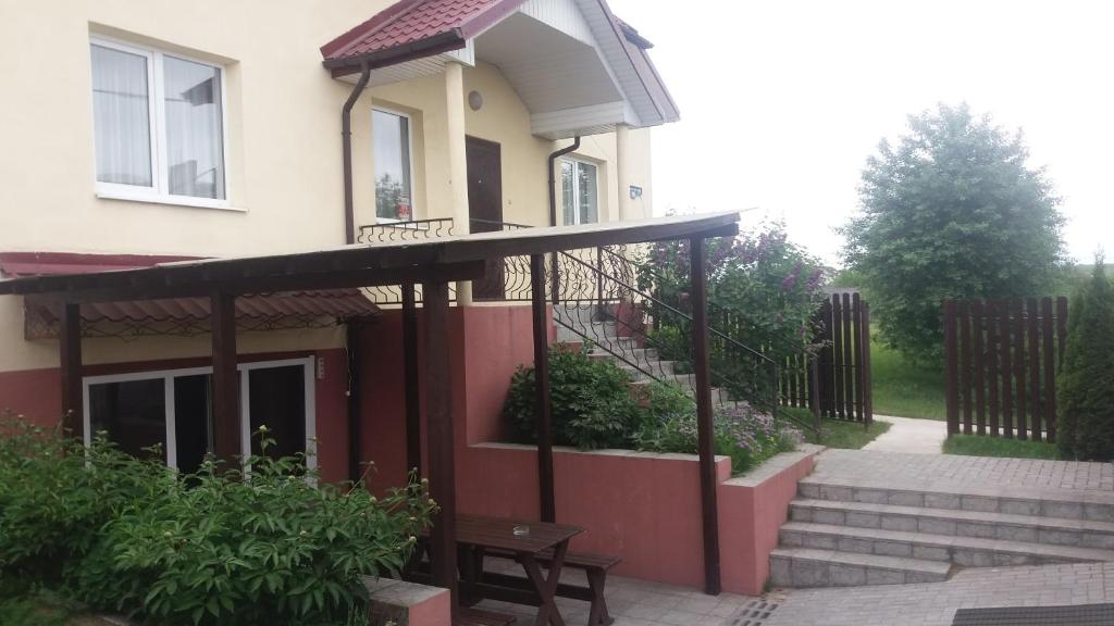 uma casa com um alpendre e um banco em frente em Usadba V Lapenkah em Grodno