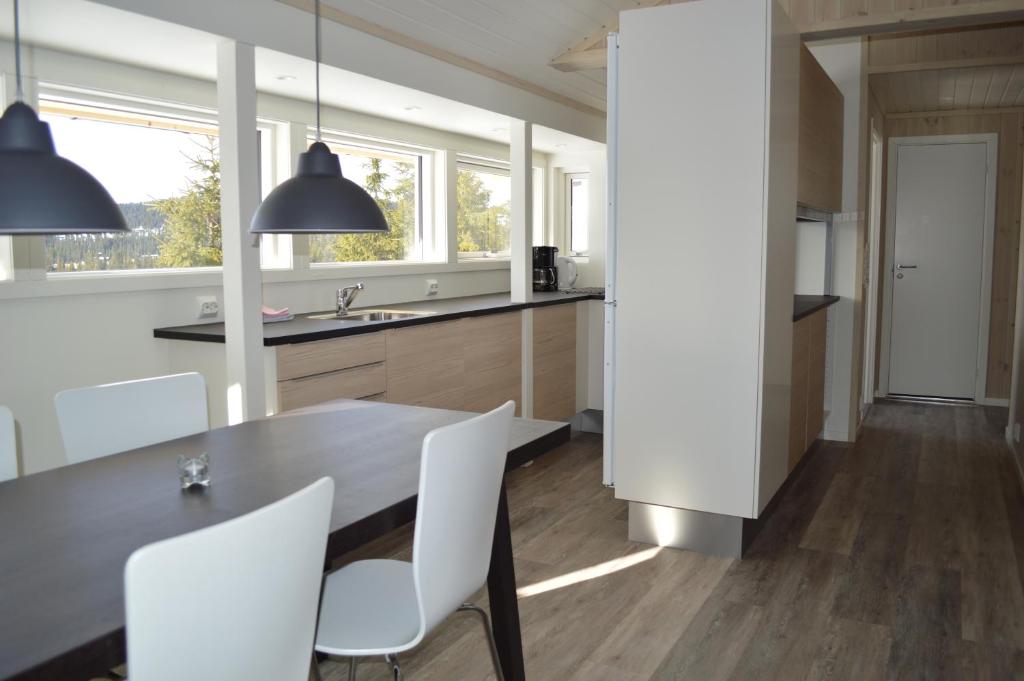 a kitchen with a dining table and white chairs at Nordseter Fjellpark, Hyttegrend in Nordseter