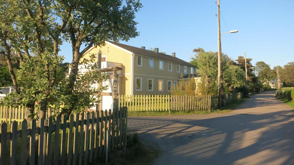 ein gelbes Haus mit einem Zaun neben einer Straße in der Unterkunft Vallersviks Vandrarhem Änggården in Frillesås