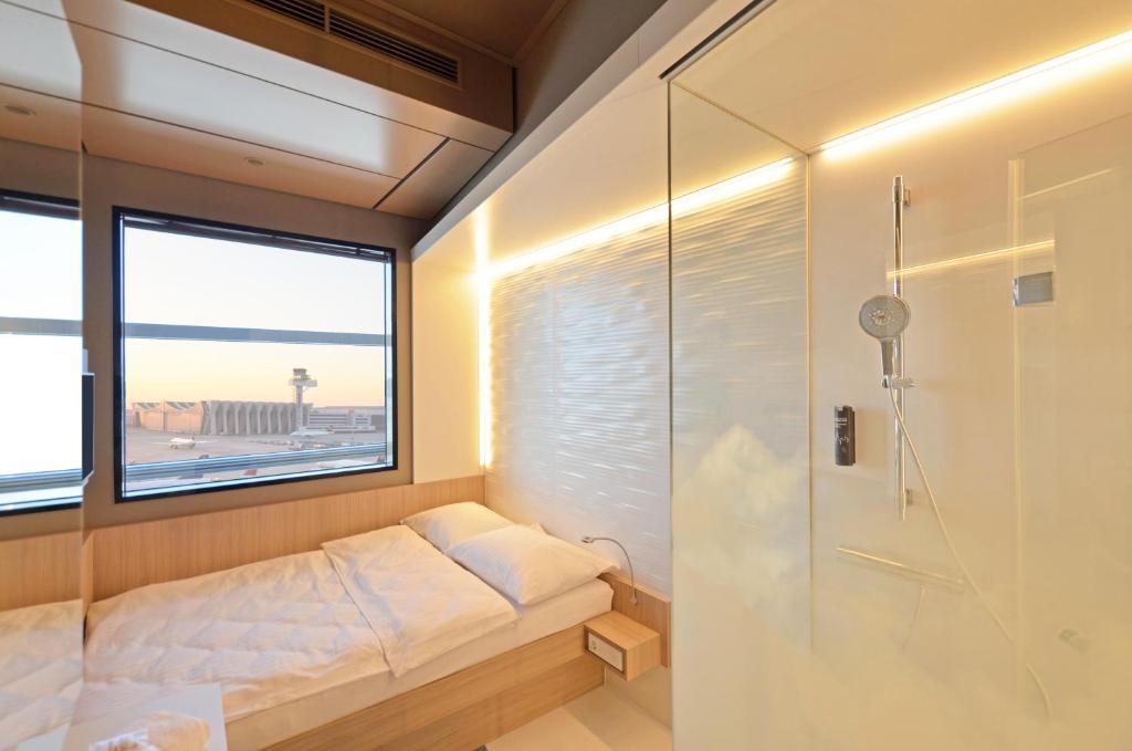 a shower room with a bed and a window at MY CLOUD Transit Hotel - Guests with international flight only! in Frankfurt