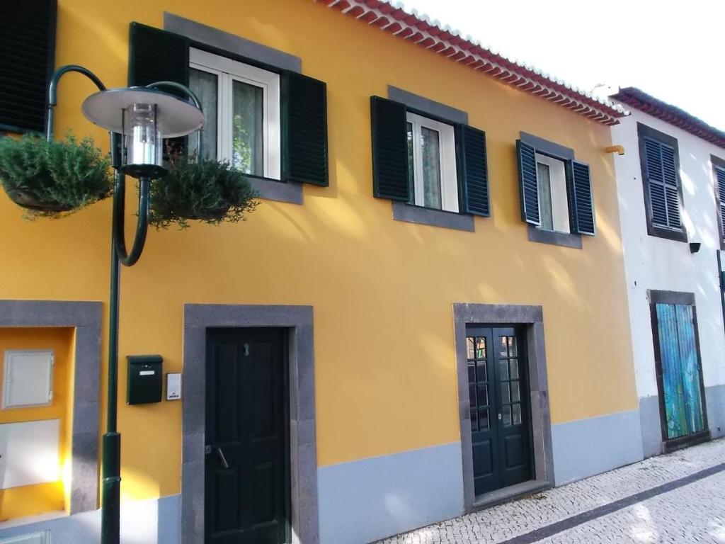 um edifício amarelo e branco com janelas pretas fechadas em Casa do Forte em Machico