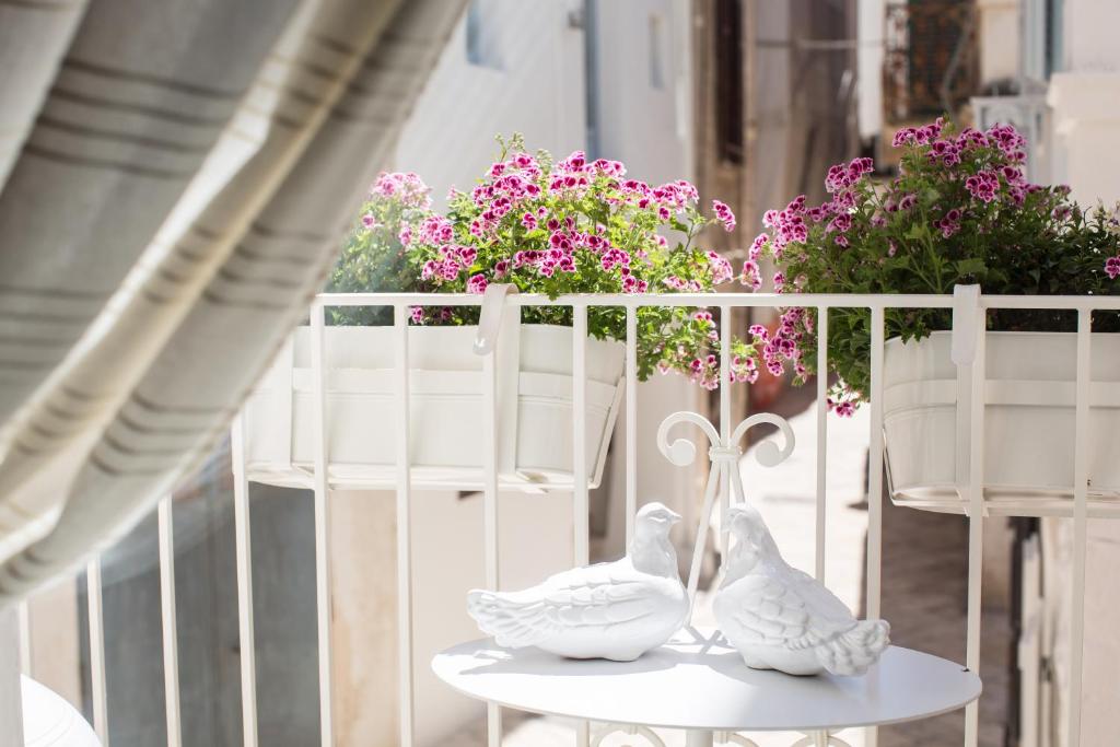 twee witte vogels zitten op een tafel met bloemen bij Trame - La Naca sul Porto in Polignano a Mare