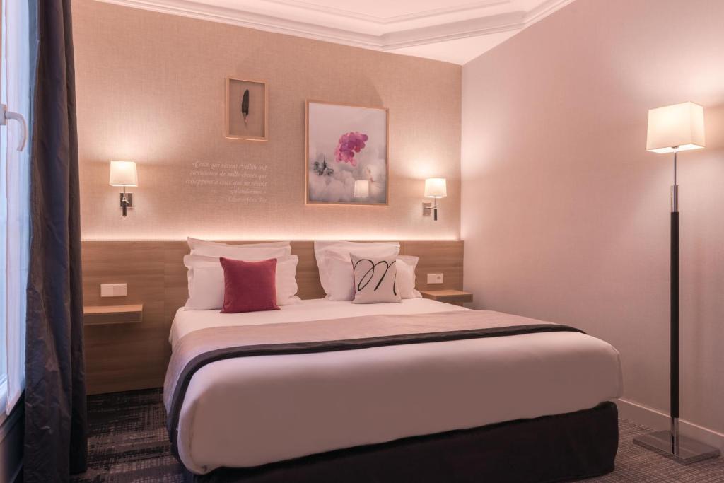 um quarto de hotel com uma cama grande com almofadas em Magda Champs Elysées em Paris