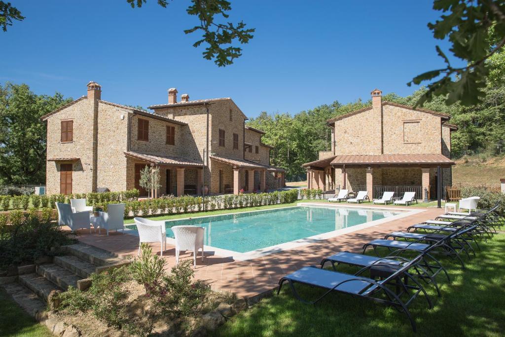 a pool in front of a house with lounge chairs at Borgo Poggiardelli in Montepulciano