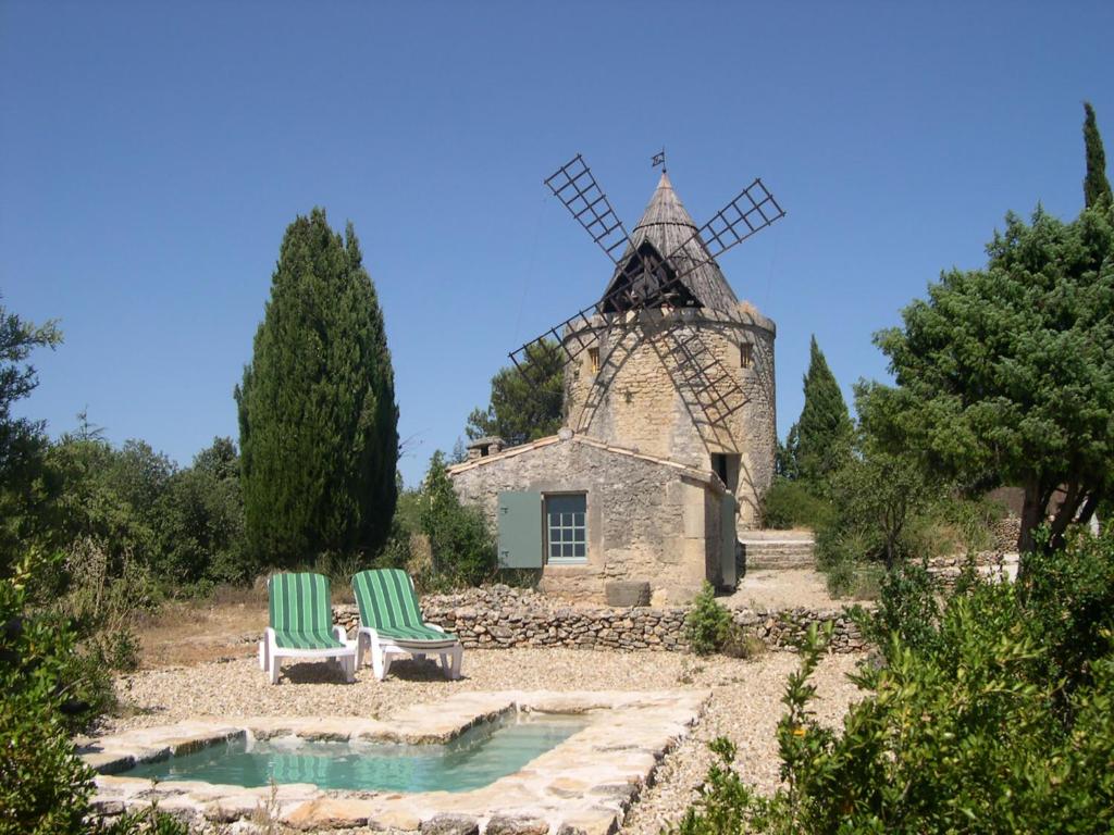 dos sillas verdes sentadas frente a un molino de viento en Moulin de maître Cornille, en Castillon-du-Gard