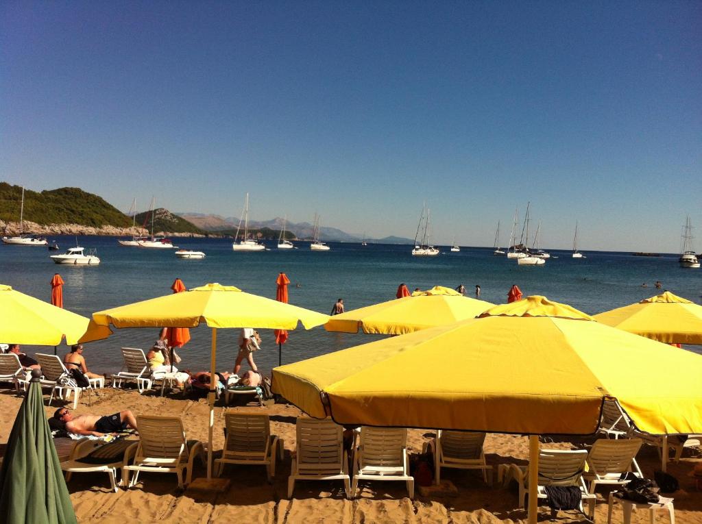 eine Gruppe gelber Regenschirme und Menschen am Strand in der Unterkunft Guesthouse Storelli in Lopud Island