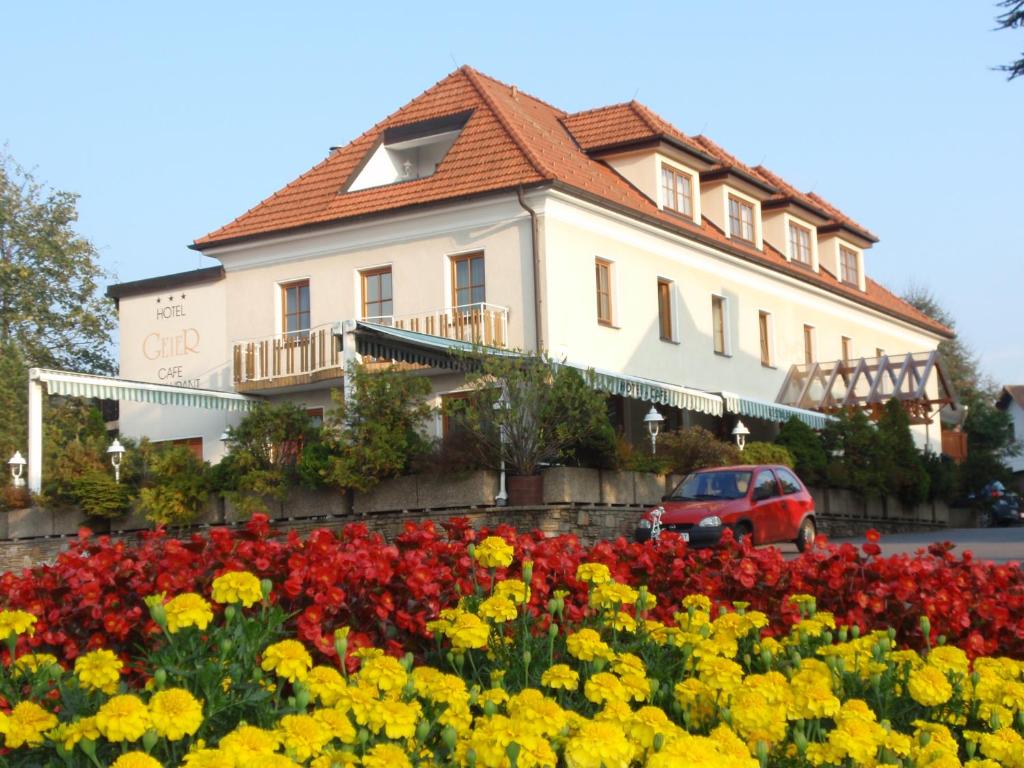 a building with a flower garden in front of it at Hotel Geier in Bad Schönau