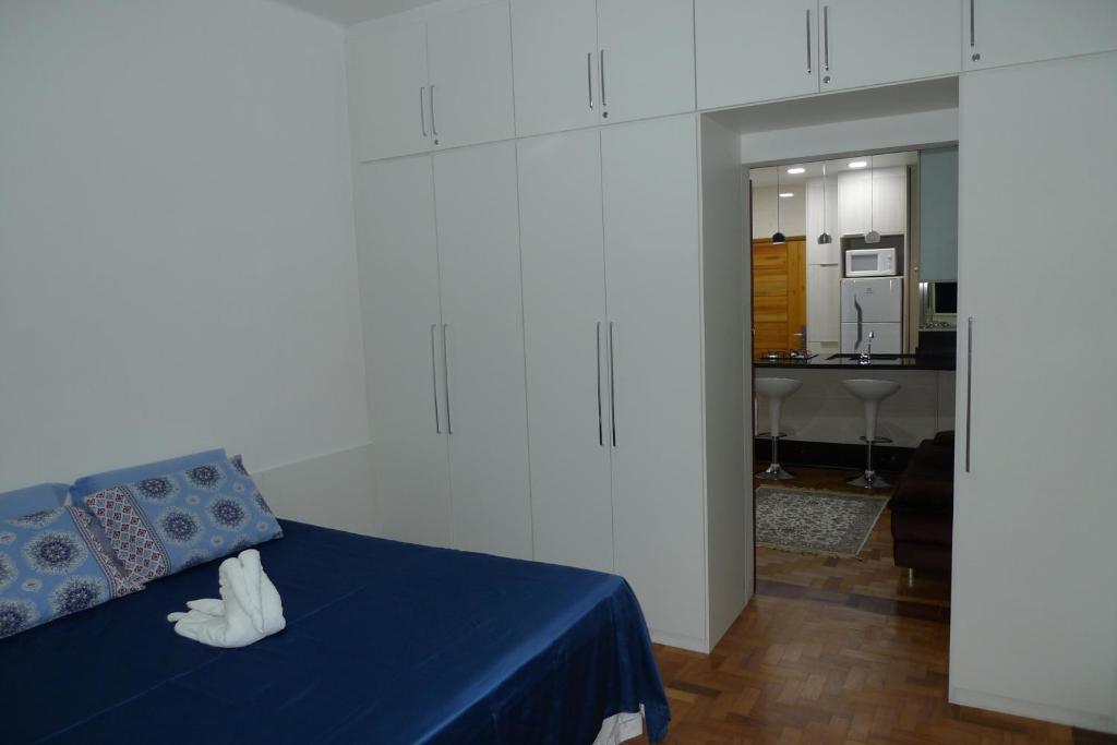a bedroom with a blue bed and a kitchen at Village Copacabana in Rio de Janeiro