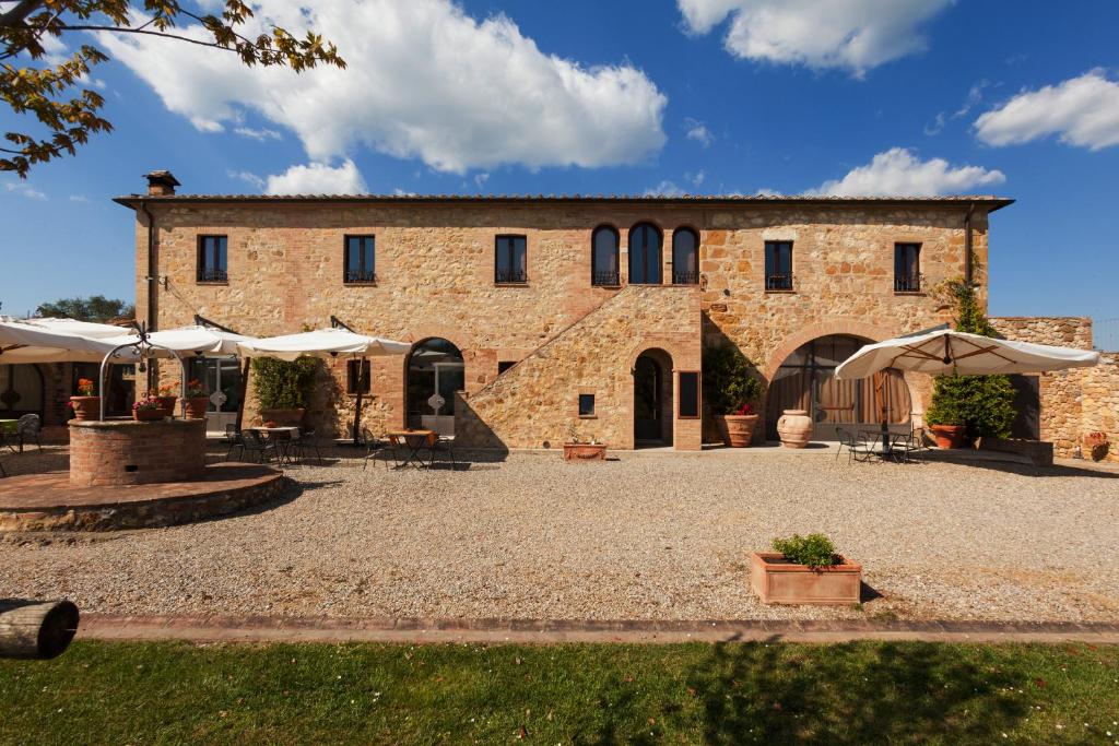 un grand bâtiment en briques avec des tables et des parasols dans l'établissement Agriturismo La Collina, à Pienza