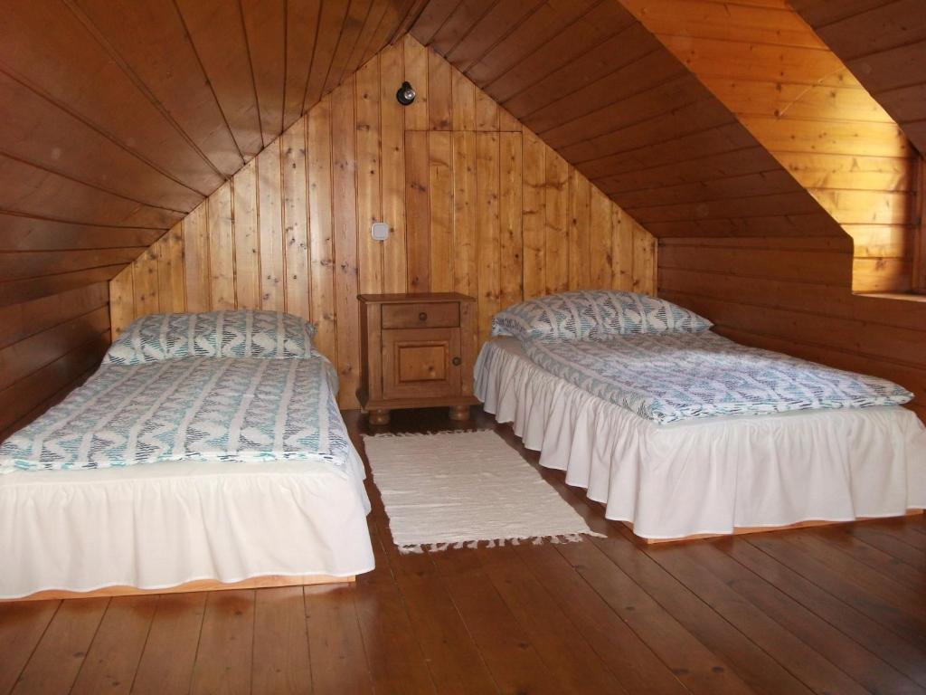 ハイドゥソボスローにあるÁlmos Apartmanのベッド2台 木製の壁の部屋