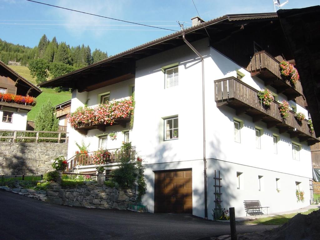 uma casa branca com caixas de flores ao lado em Janserhof em Obertilliach