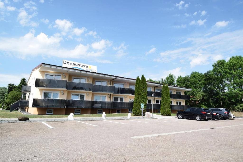 ein Hotel mit Autos auf einem Parkplatz in der Unterkunft Aparthotel Donaustern in Asbach-Bäumenheim