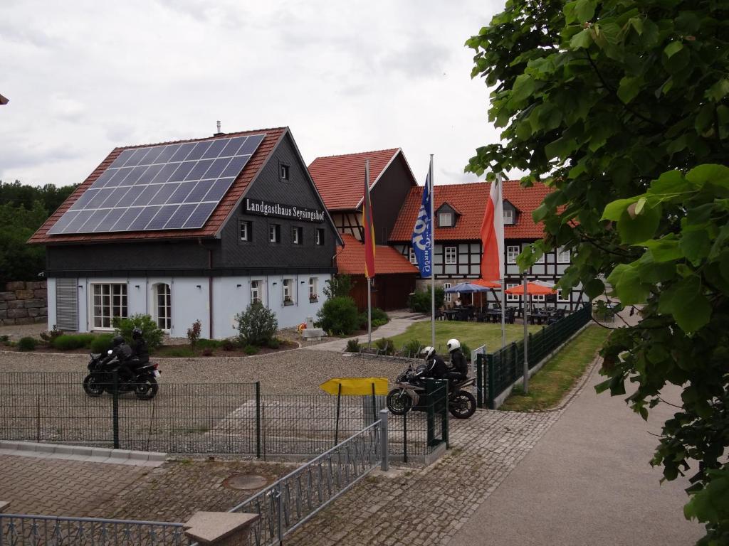 two people on motorcycles in front of a building with solar panels at Landgasthaus zum Seysingshof in Bad Colberg