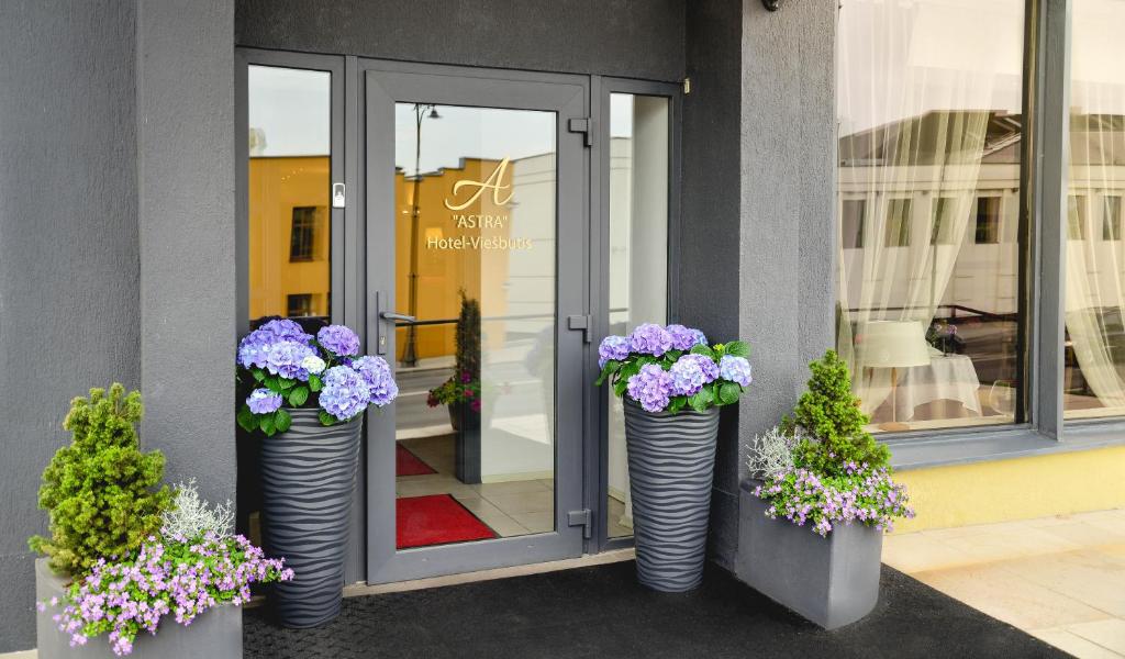 three vases filled with flowers in front of a store at Astra Hotel in Klaipėda