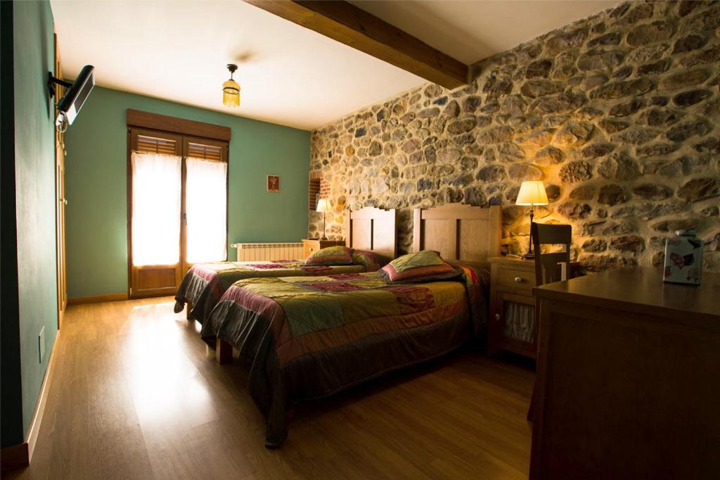 a bedroom with a bed and a stone wall at Posada El Arrabal in Arenas de Iguña