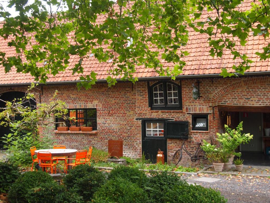 uma casa de tijolos com uma mesa e cadeiras em frente em Grote Goesting holiday house em Wevelgem