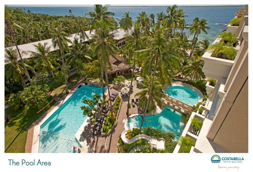 an aerial view of a resort with two pools and palm trees at Costabella Tropical Beach Hotel in Mactan