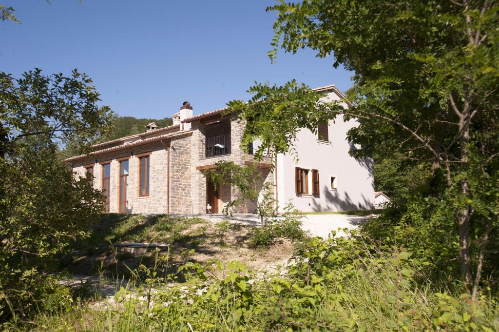 uma velha casa de pedra com árvores em frente em Mazzamurello em Caldarola