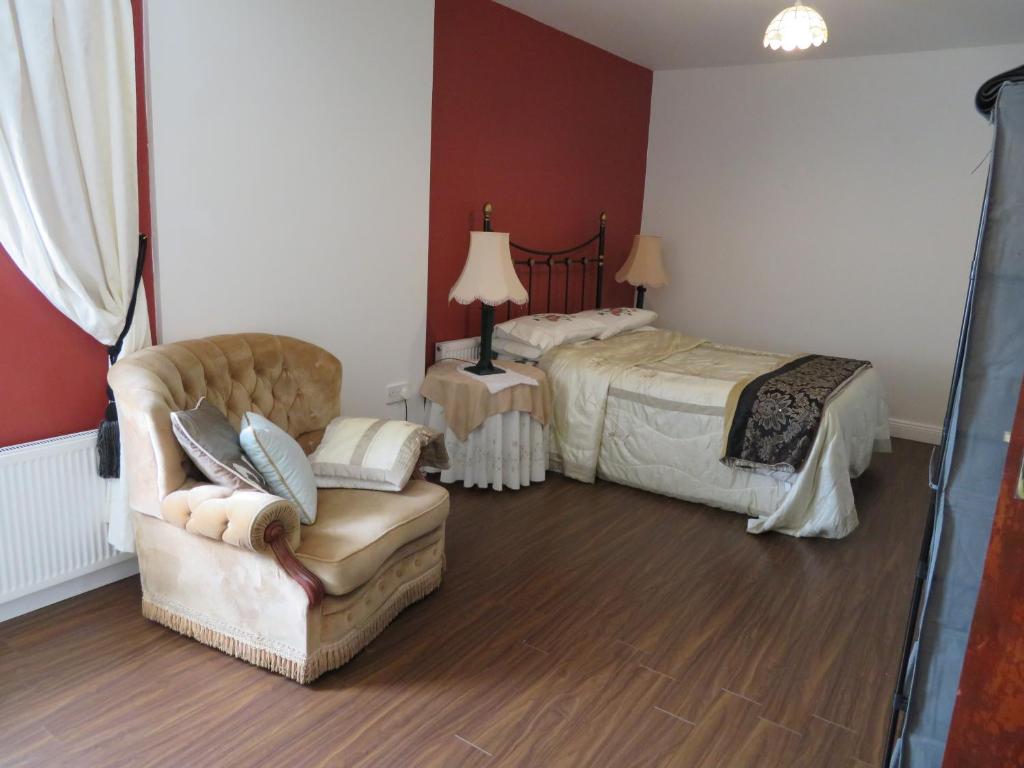 een slaapkamer met een bed, een bank en een stoel bij Leam Cottage in Belmullet