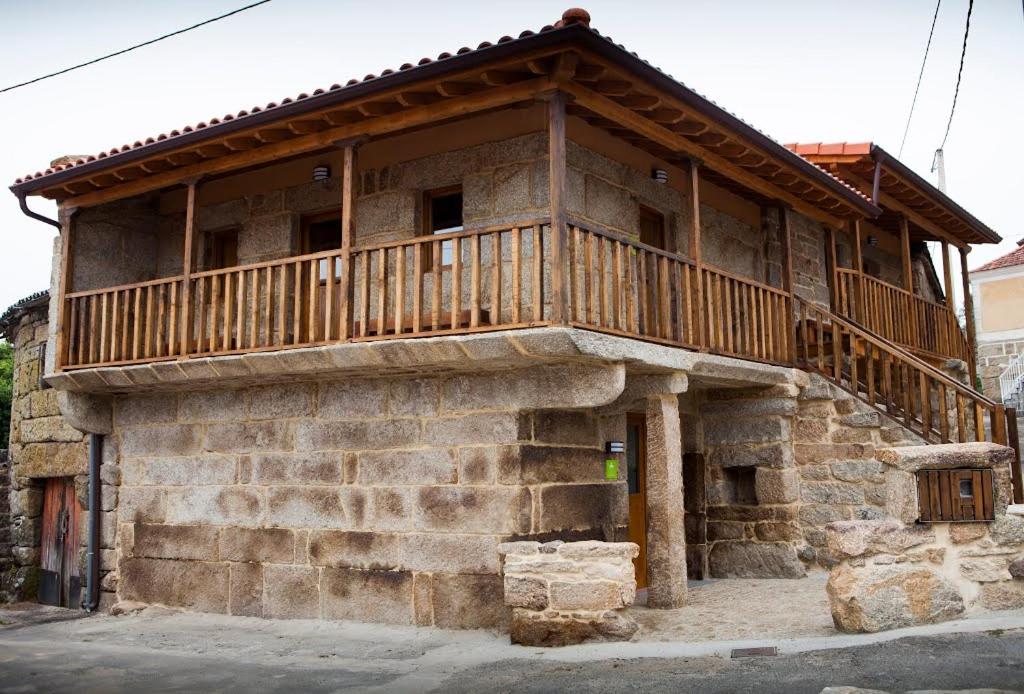- un bâtiment en pierre avec un balcon sur le côté dans l'établissement Albergue do Xurés, à Maus de Salas