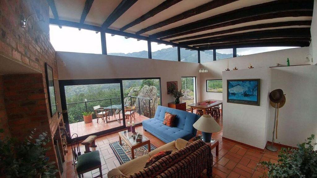 a living room with a blue couch and a large window at Farallones de Sutatausa El Rincón in Sutatausa