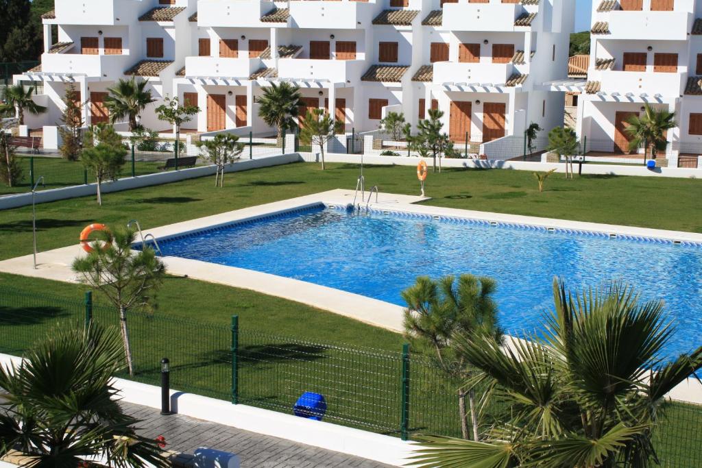 una imagen de una piscina frente a un edificio en Apartamentos Turísticos La Carrajolilla, en Chiclana de la Frontera