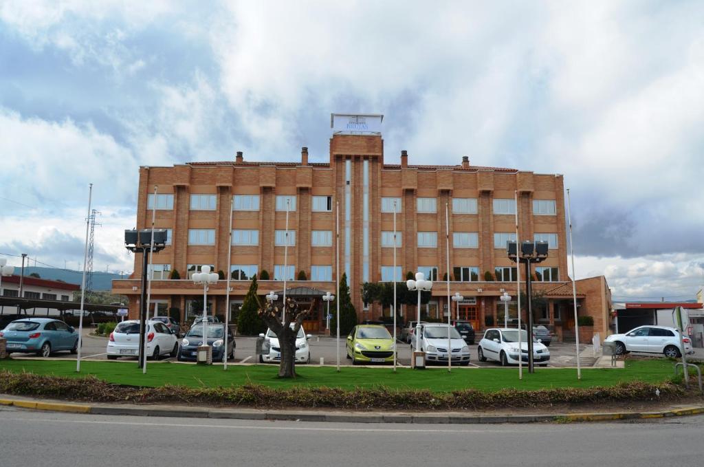 塔拉桑納阿拉貢的住宿－布魯哈斯伊露酒店，一座大型砖砌建筑,停车场内有车辆停放