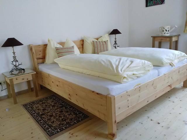 uma cama de madeira com lençóis brancos e almofadas em Gartler's Appartements em Kalsdorf bei Graz