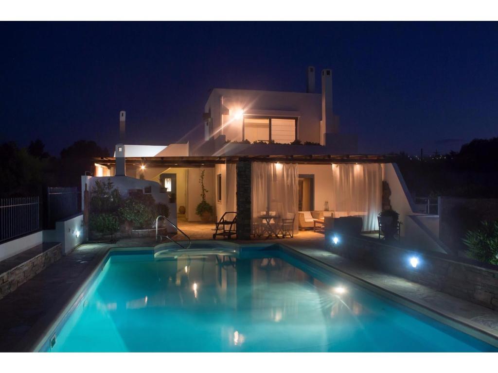 a swimming pool in front of a house at night at Villa Blue Island in Artemida