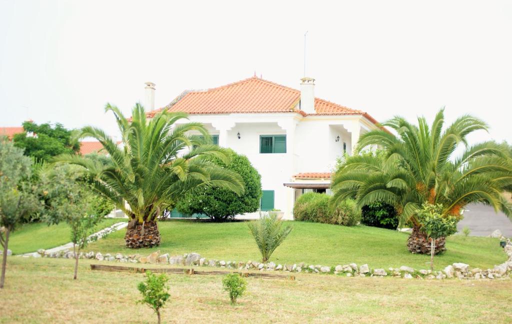 uma casa branca com palmeiras num quintal em Quinta da Perdiz Country House em Santarém